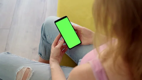 Rear view of phone with green screen chroma key in hands of blonde in pink top Stock Footage 200840958