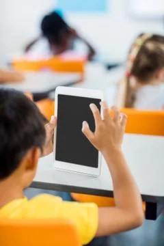 Rear view of pupil using tablet pc in classroom Foto stock