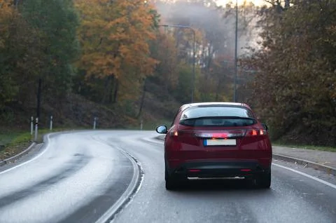 Rear view of a red car on a bend in an autumn road Stock Photos