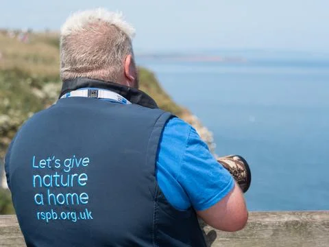 A rear view of an RSPB warden looking out to sea Stock Photos