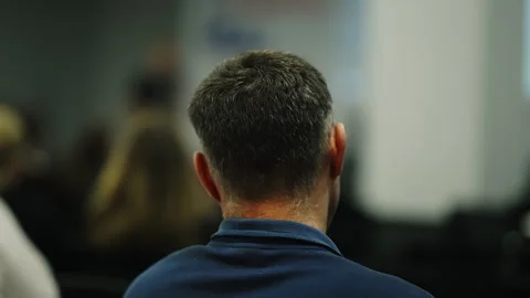 Rear view of a seated attendee focusing on a presentation at an indoor Stock Footage 332196751