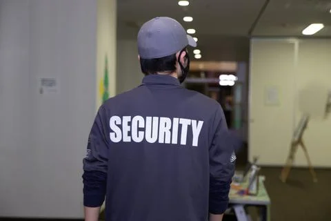 Rear view of security guard in uniform patrolling in commercial mall Stock Photos