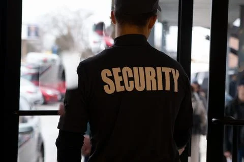Rear view of security guard in uniform patrolling in commercial mall Stock Photos