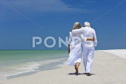 Rear view of senior couple walking alone on a tropical beach Stock-Fotos