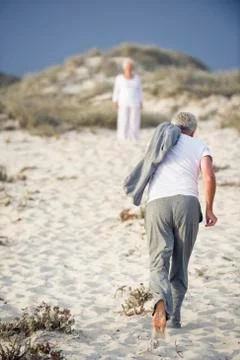 Rear view of a senior man running towards a woman standing in the background Stock Photos