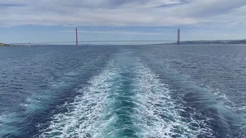 Rear view of a ship's wake in the ocean with a large suspension bridge Vídeos de archivo 335044871