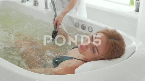 Rear view shot of a woman enjoying hydromassage in whirl pool bath Stock Photos