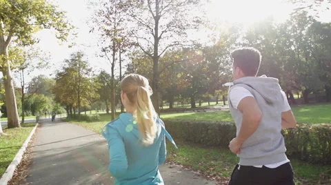 Rear View Shot Of Young Athletic Couple Jogging Through Sunlit Park Stock Footage 42159741