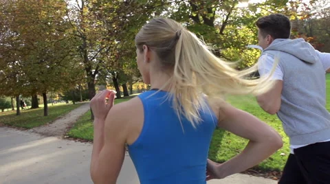 Rear View Shot Of Young Athletic Couple Jogging Through Sunlit Park Stock Footage 42160389