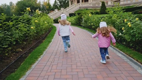 Rear view of the sister running along the sidewalk Stock Footage 80605703