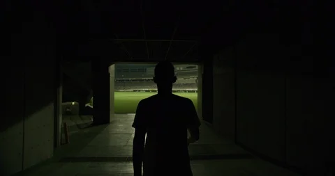 Rear view of soccer player walking to outdoor football stadium, dark corridor Stock Footage 124677152