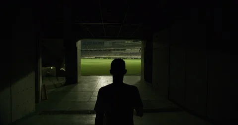 Rear view of soccer player walking to outdoor football stadium, dark corridor Stock Footage 124677398