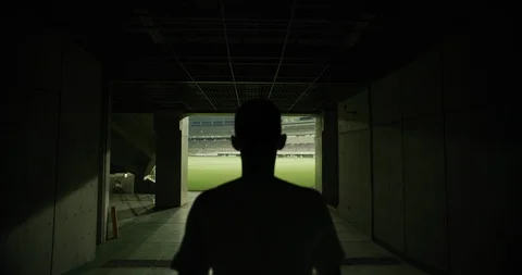 Rear view of soccer player walking to outdoor football stadium, dark corridor Video stock 124677520