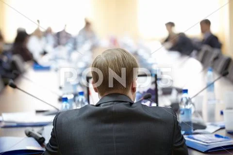 Rear view of speaker with laptop in front presenting his report to audience Stock Photos