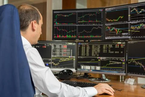 Rear view of stock trader analyzing data at multiple computer screens. Rea... Foto stock