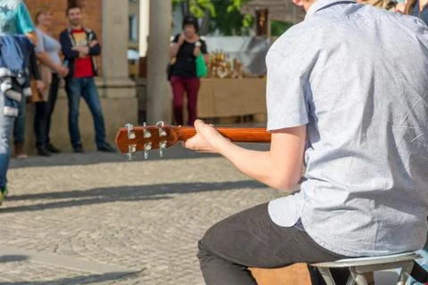 Rear view of street artist playing guitar in front of live audience. Stock Photos