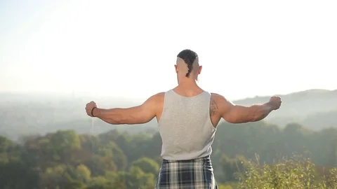 Rear view. a strong man with large muscles in his hands spreads the hands to the Stock Footage 126495874