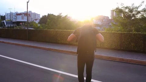 Rear view of a student in the sunset light walking through the city center. Stock Footage 140286298