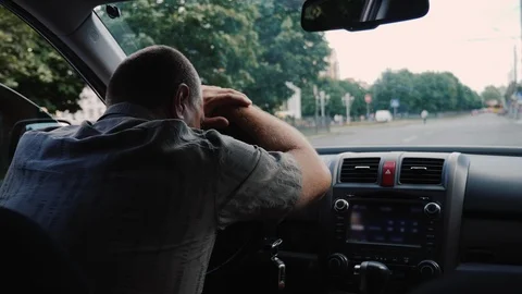 Rear view of Tired middle-aged man put his head on the wheel of a car Stock Footage 111473584