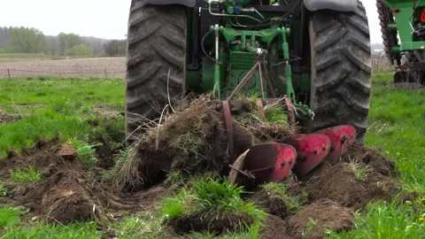 Rear View of Tractor Pulling Red Plow Through Spring Farm Field Vídeos de archivo 346412407