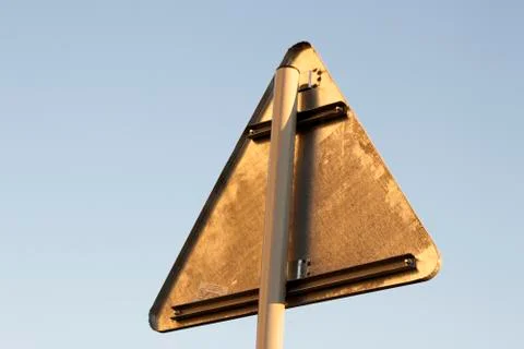 Rear view of triangular abstract blank empty road sign posted high on metal p 写真素材
