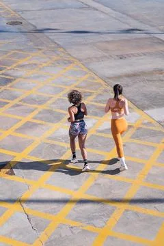 Rear view of two friends running along city road Stock Photos