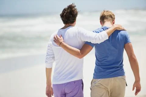 Rear view of two men walking with their arms around each other Stock Photos