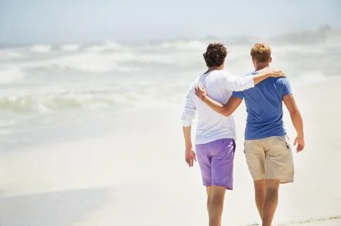 Rear view of two men walking with their arms around each other Stock Photos