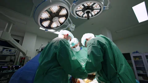 Rear view of two surgeons bent over the patient in operational room.  Stock Footage 252786576