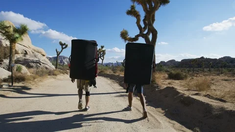 Rear view of two tourists with backpacks walking through desert Stock Footage 101961847
