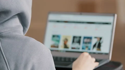 Rear view unknown hacker young programmer web designer in hood look at laptop Stock Footage 195742524