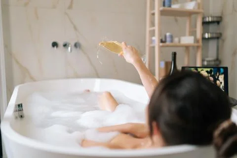 Rear view of unrecognizable charming young woman pouring out champagne in Stock-Fotos