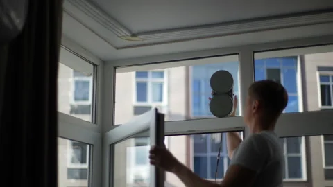 Rear view of unrecognizable man launched automatic robot for washing windows in Stock Footage 263733775