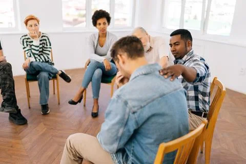 Rear view of unrecognizable sad crying man sharing life problem grief with Stock Photos