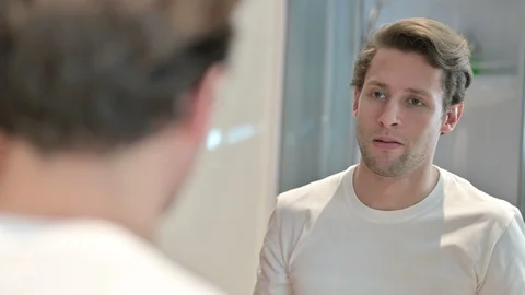Rear View of Upset Young Man looking Himself in Mirror Stock-Footage 124200725