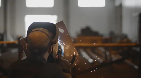Rear view Welding Engineer weld metal pad blank. Lot of bright sparks, smoke and Stock Footage 57513554