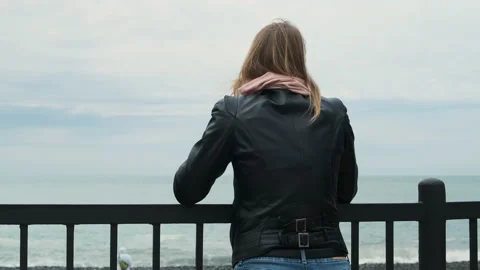Rear view of white-haired blonde woman in black leather jacket leaning on Video stock 154331129
