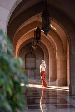 Rear view of woman exploring mosque corridor with islamic architecture in oman Stock Photos
