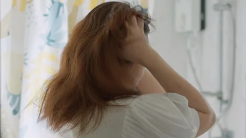Rear view of a woman's scratching her scalp intensely, indicating an itchy scalp 動画素材 327847184