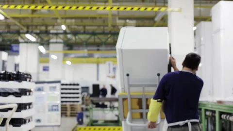 Rear View of Worker Moving Refrigerator on Assembly Line - 4K  Stock Footage 306333729