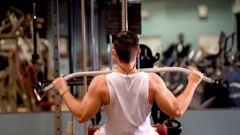 Rear view of young bodybuilder doing lat pulldowns on a machine. Stock Footage 98288077