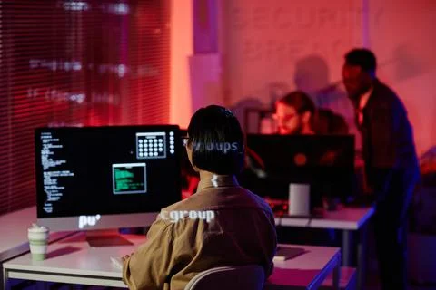 Rear view of young contemporary programmer sitting in front of computer screen 库存照片