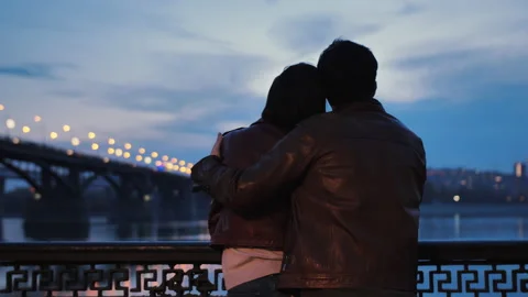 Rear view of a young couple hugging in the evening against a background of Stock-Footage 136901844