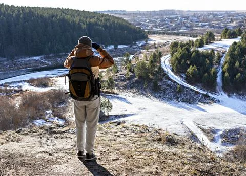 Rear view of a young man with backpack standing on mountain and looking view Stock Photos