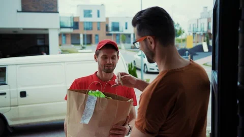Rear view of young man customer receiving food bag from delivery services. Close Stock Footage 113793295