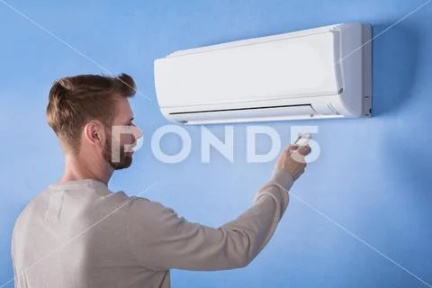 Rear View Of A Young Man Operating Air Conditioner Stock Photos