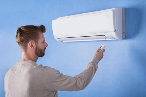 Rear View Of A Young Man Operating Air Conditioner Stock Photos
