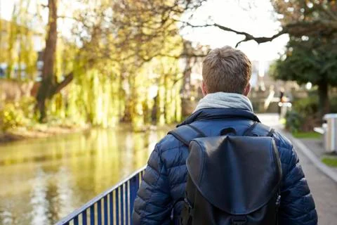 Rear View Of Young Man Walking By River In City Stock Photos