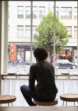 Rear View Of Young Man By Window Using Mobile Phone In Cafe Stock-Fotos