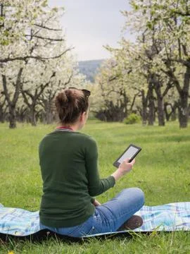 Rear view of a young woman outdoors reading on her ebook Stock Photos